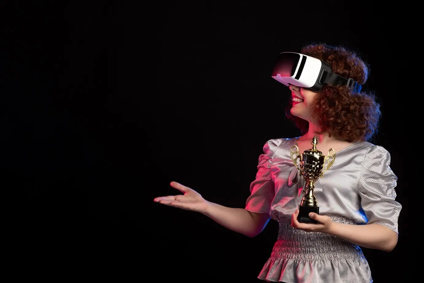 Junge Frau mit VR-Headset, eine Tasse auf einem dunklen Schreibtisch, beim Spielen eines VR-Videospiels.